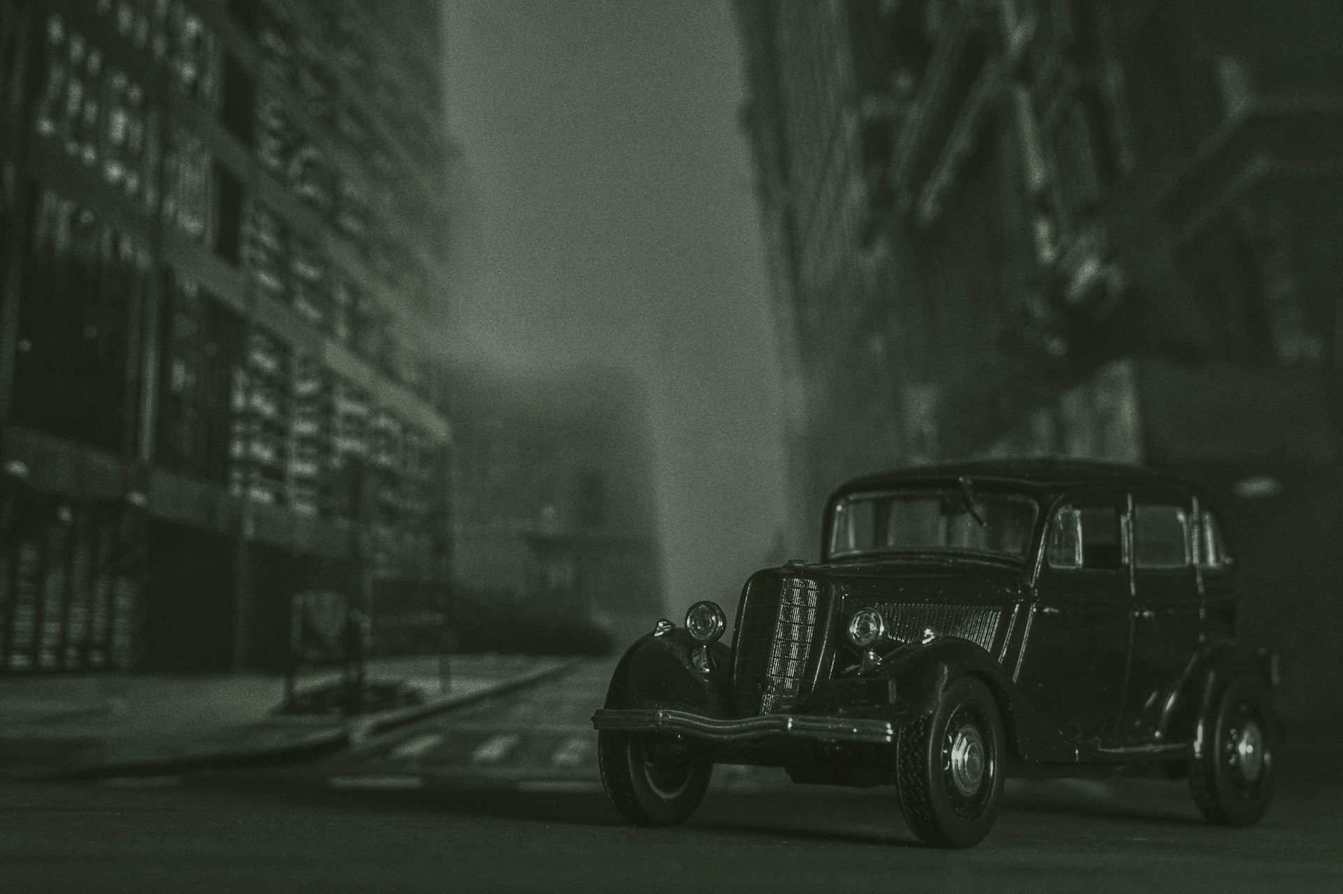 a black and white photo of an old car on a city street